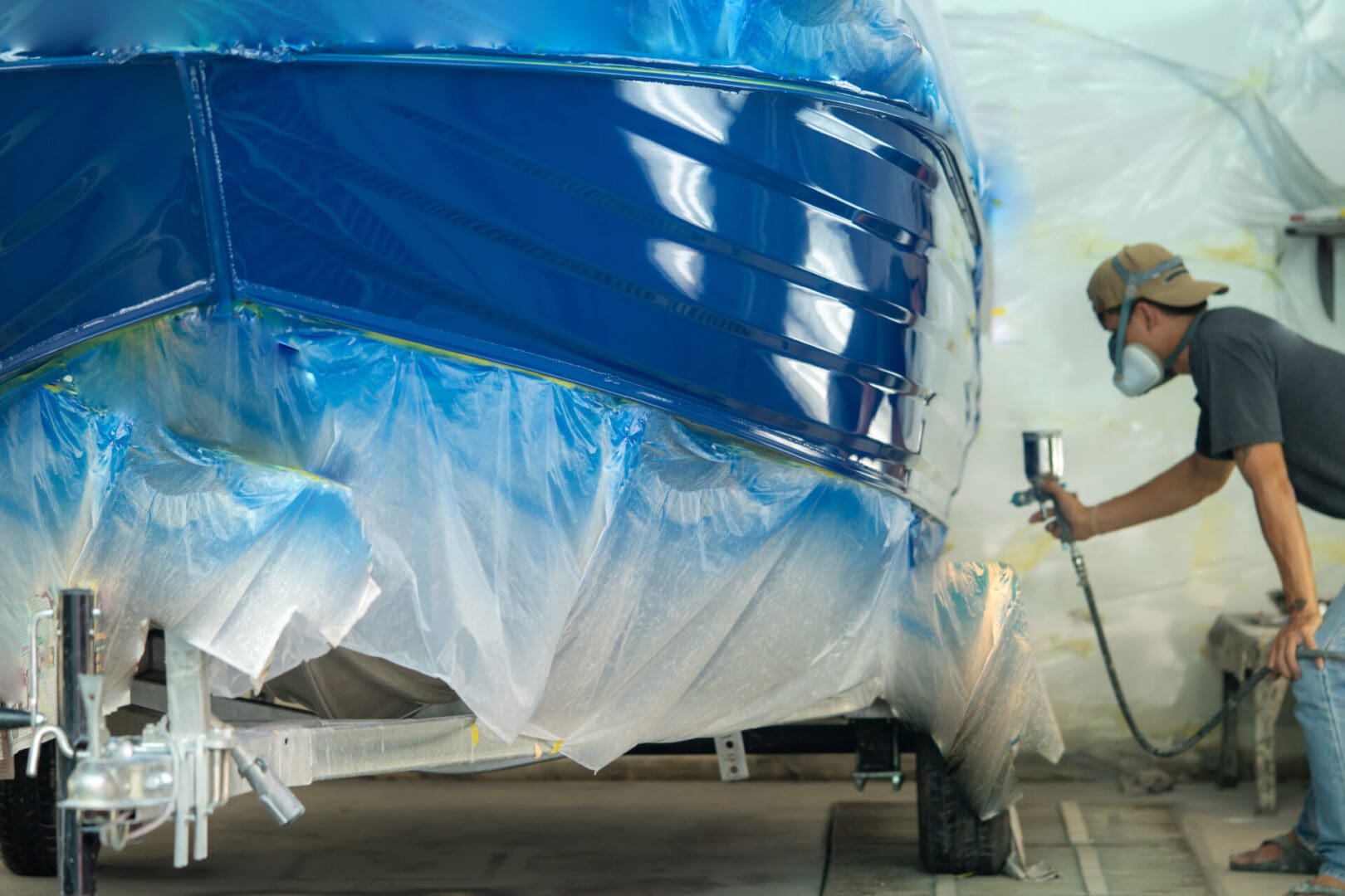 Repairman fixing by painting boat body and painting boat using spray gun
